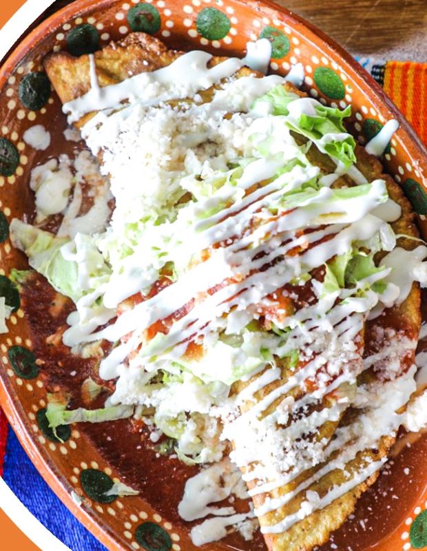 Quesadillas de maíz bañadas en salsa con crema, queso y lechuga